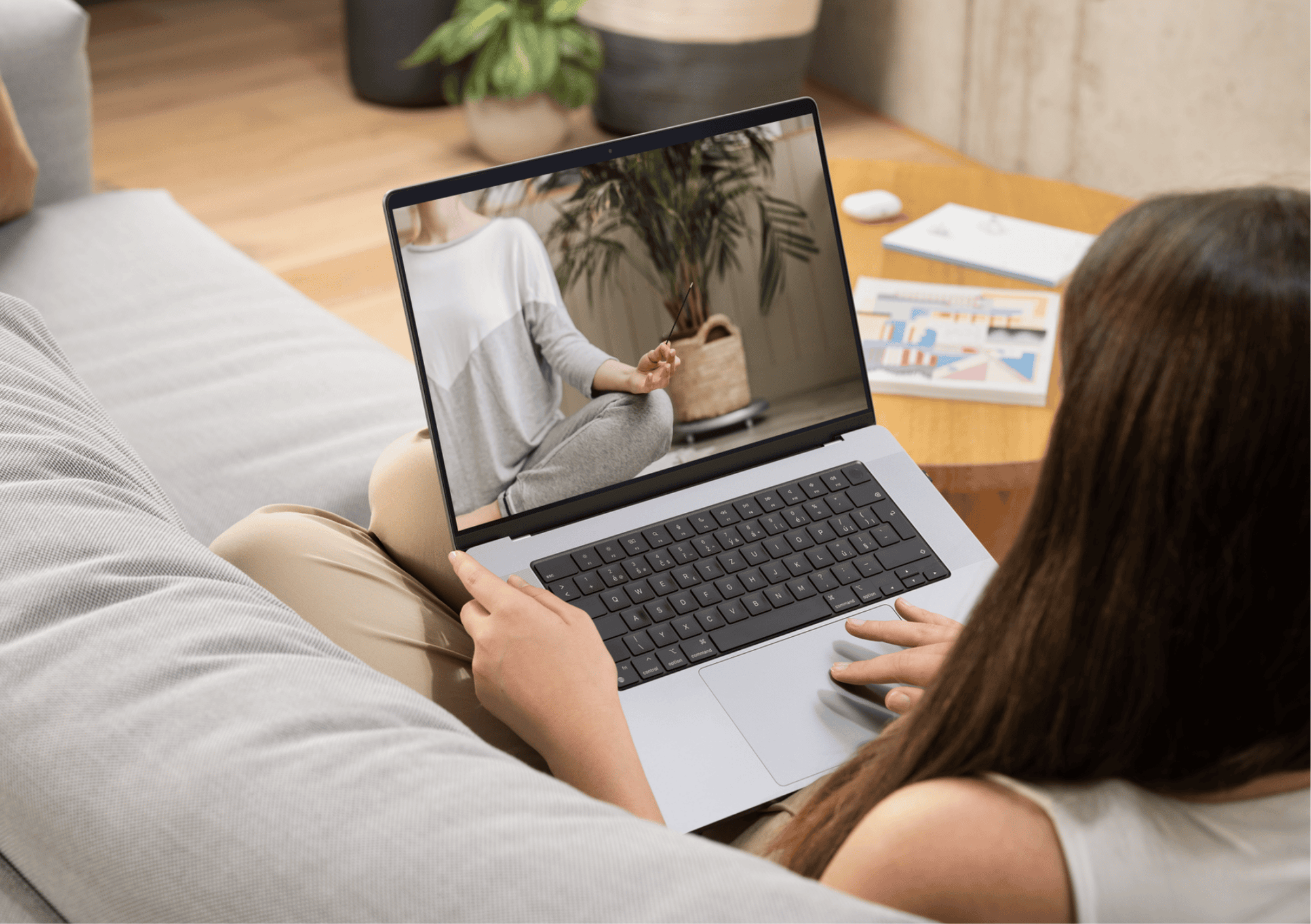 Frau verfolgt am Laptop eine Online-Meditation mit Räucherstäbchen und entspannter Atmosphäre