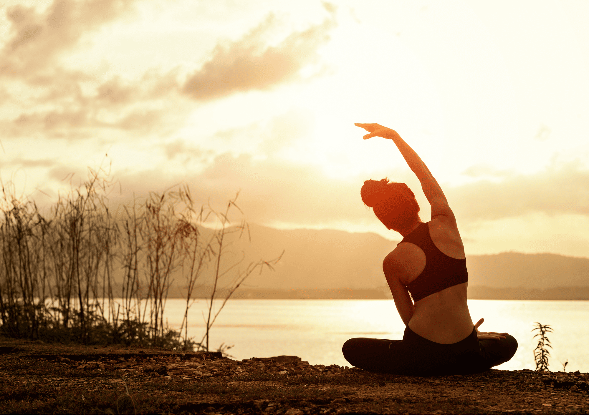 Frau praktiziert Yoga am See im Sonnenaufgang – Symbol für Achtsamkeit und Balance