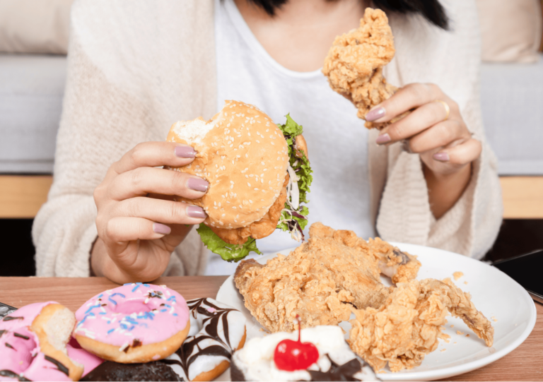Frau isst hastig Fast Food mit Burger, Donuts und Hähnchen in emotionalem Moment