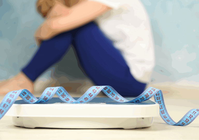 Frau sitzt traurig hinter Waage mit Maßband – Symbol für Essstörung und seelischen Druck