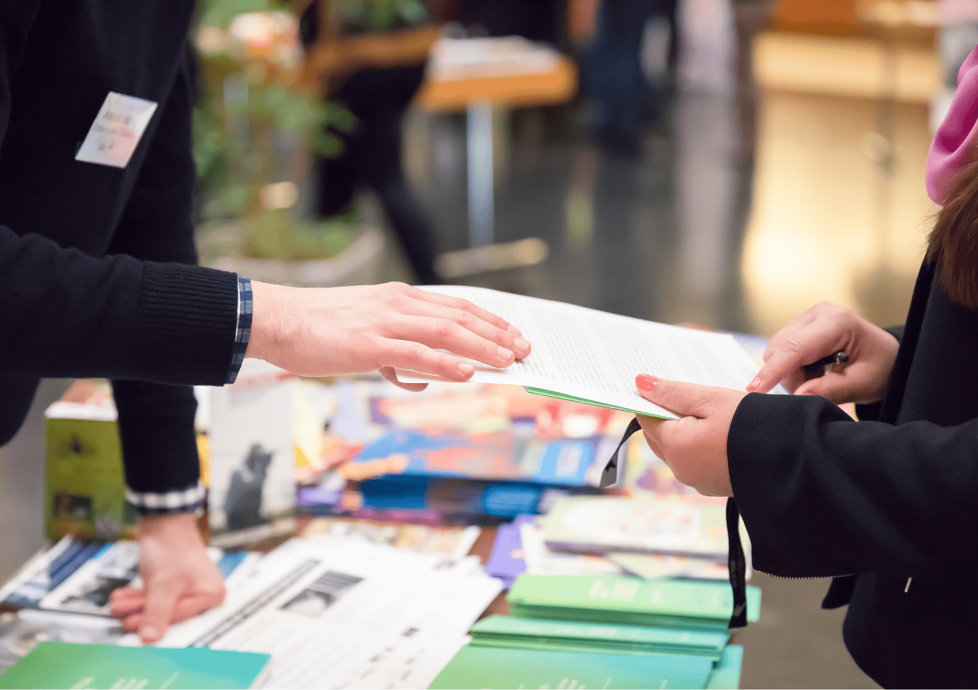 Zwei Personen im Gespräch an einem Infostand – Übergabe einer Informationsbroschüre
