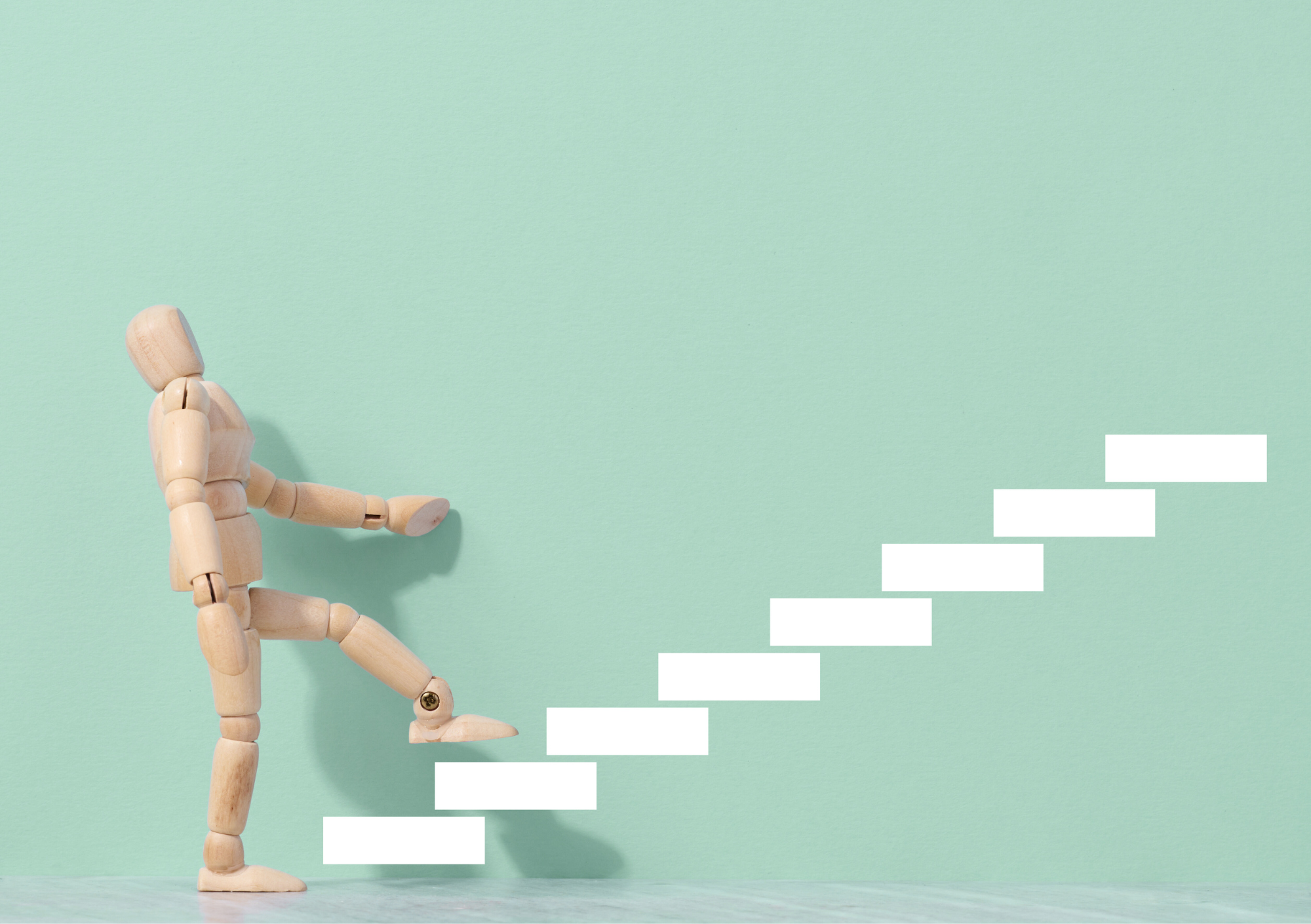 Holzfigur steigt symbolisch Stufe für Stufe eine Treppe hinauf – Sinnbild für persönliche Entwicklung