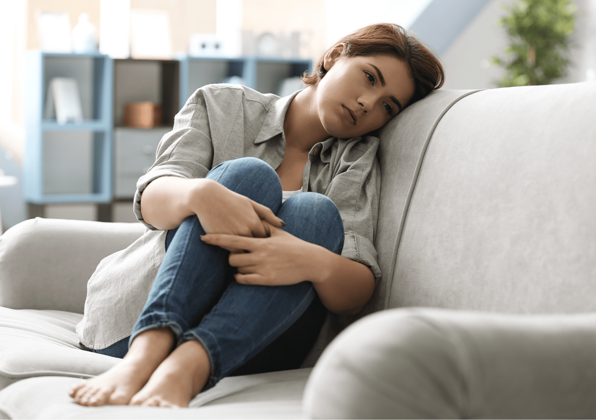 Nachdenkliche Frau sitzt allein auf dem Sofa – Symbol für Einsamkeit und emotionale Leere