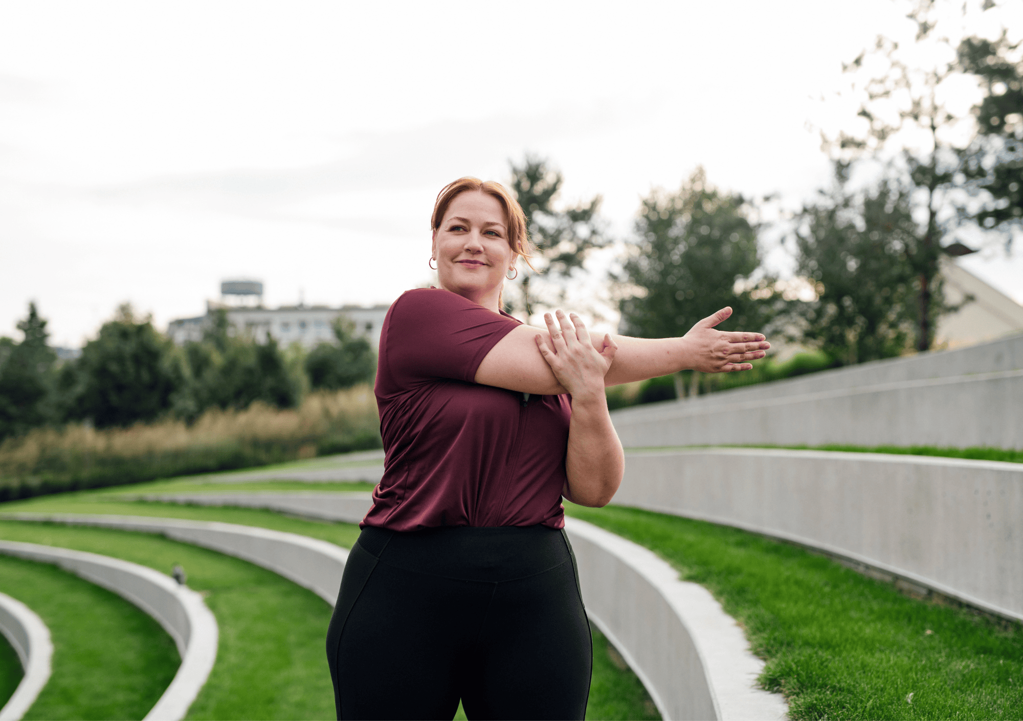 Frau dehnt sich im Park und zeigt, dass Sport mit jedem Körper Spaß machen kann