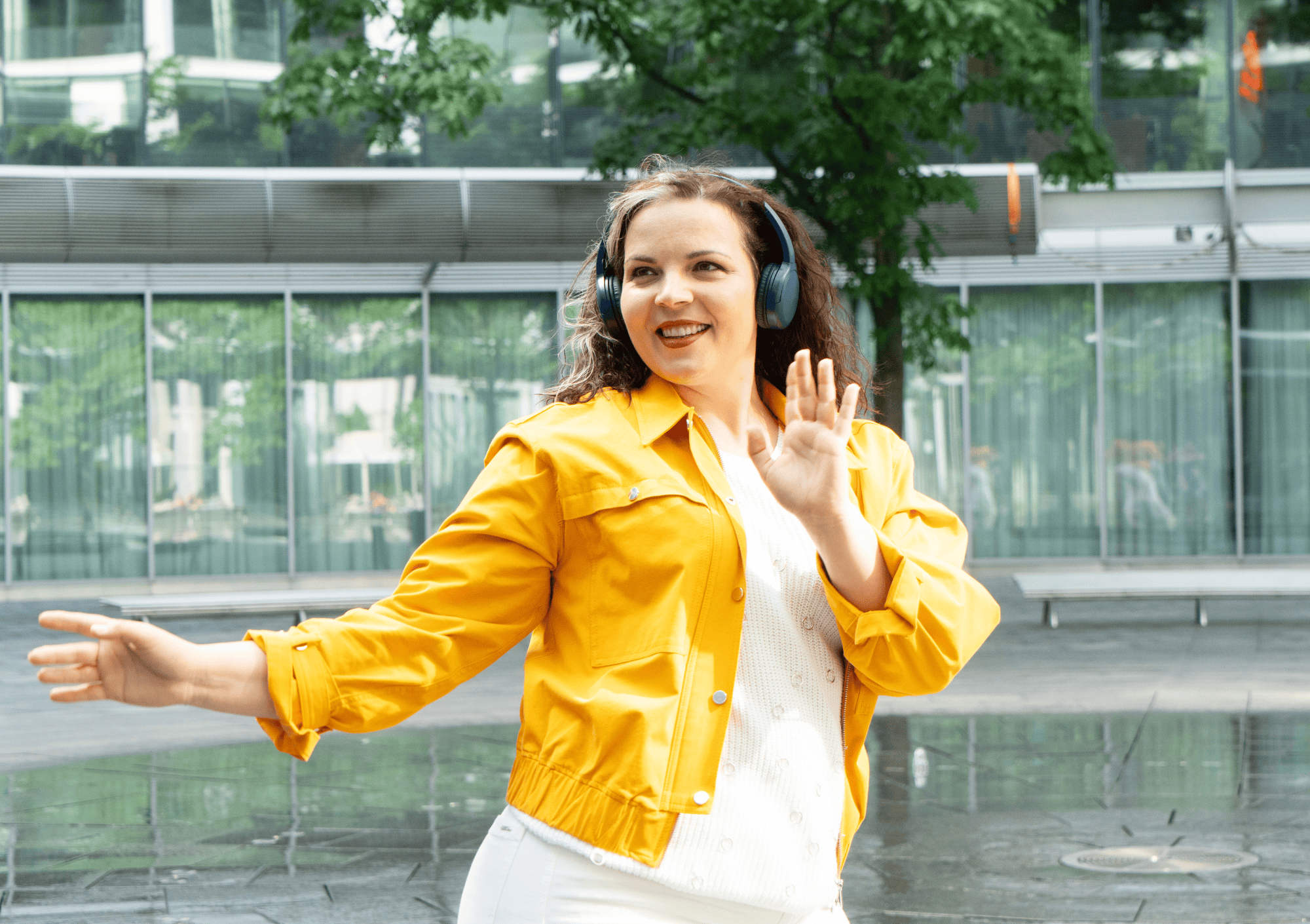 Frau tanzt mit Kopfhörern in der Stadt – Ausdruck von Selbstbewusstsein und Körperakzeptanz