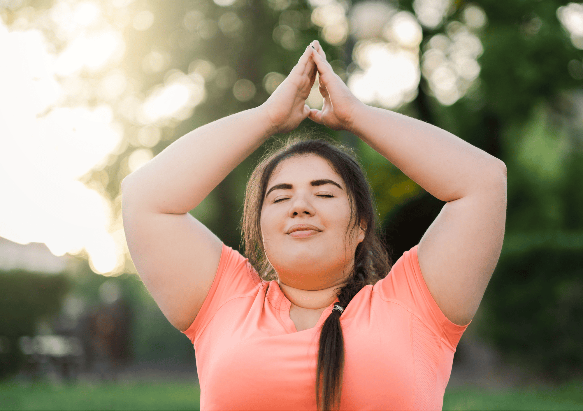 Frau meditiert mit erhobenen Armen im Freien – Fokus auf Körperfunktionen und Dankbarkeit