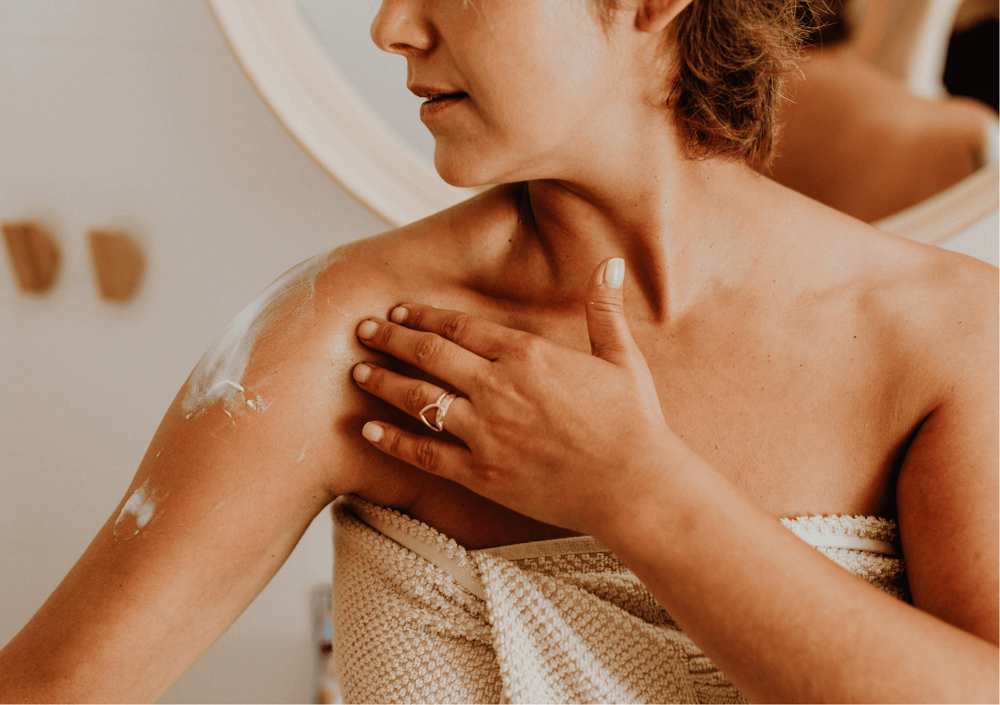 Frau cremt achtsam ihre Schulter ein – Symbol für Körperpflege und Selbstannahme