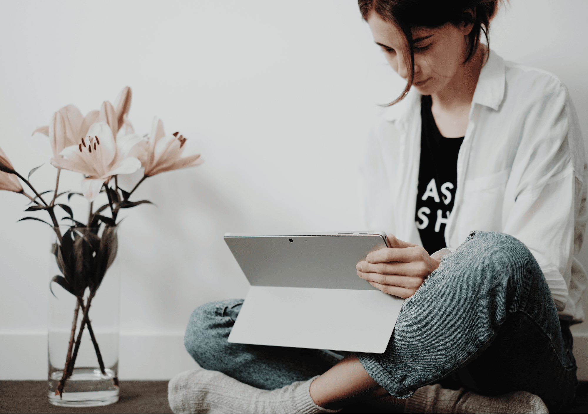 Junge Frau sitzt am Boden mit Tablet – Online-Coaching zur Selbstliebe in ruhiger Atmosphäre