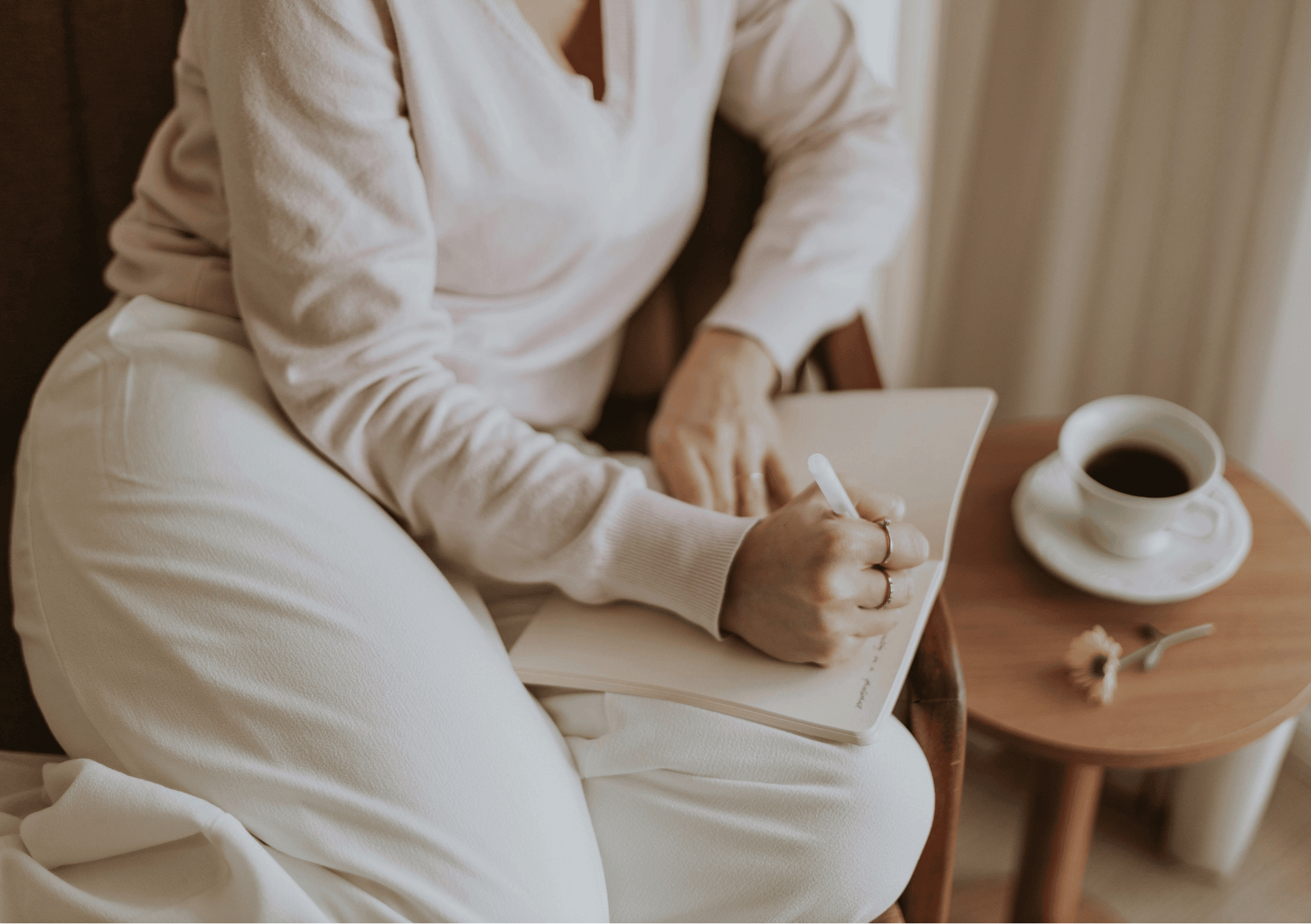 Frau schreibt in ihr Journal, neben ihr eine Tasse Kaffee – achtsamer Moment der Selbstreflexion